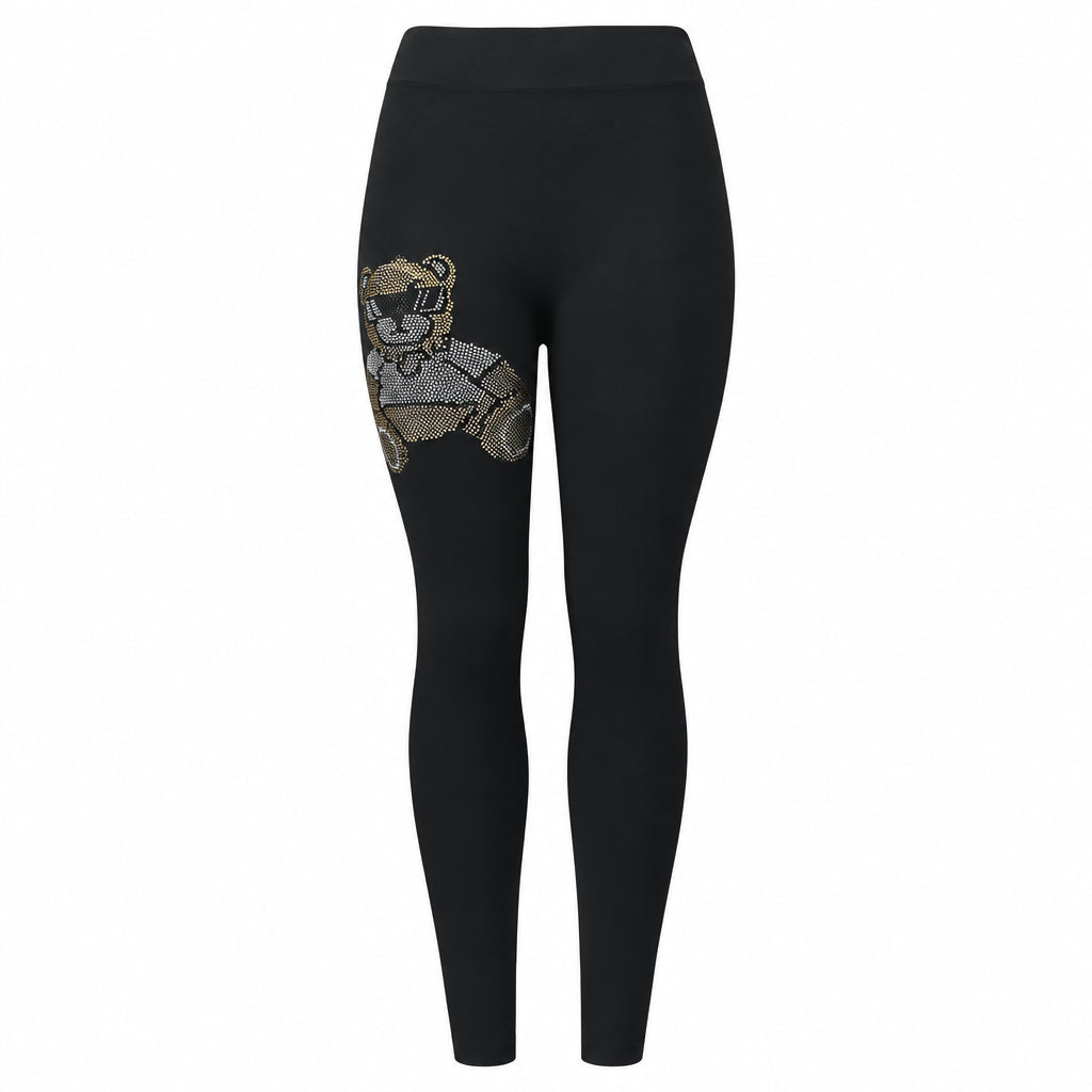 A pair of black leggings with a gold-colored bear and moon design on the lower left side.