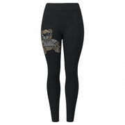 A pair of black leggings with a gold-colored bear and moon design on the lower left side.