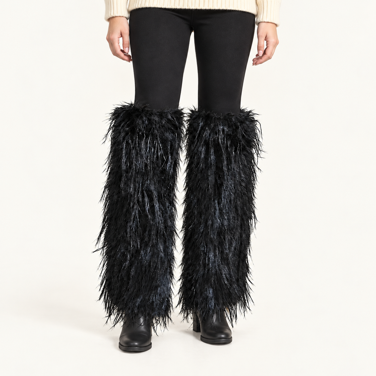Black shaggy faux fur leg warmers worn by a human model over black leggings and boots